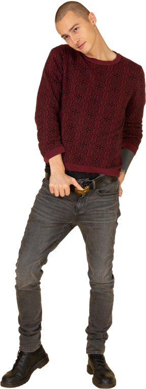 Front view of a young man in red pullover touching belt