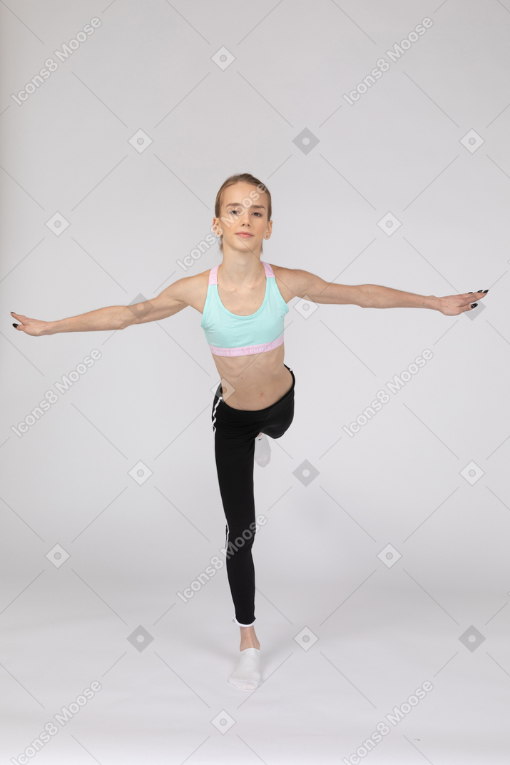 一个年轻的女孩，在她的腿上保持平衡的运动服的前视图