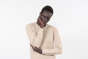 A young black man in a grey sweater standing alone on the white background