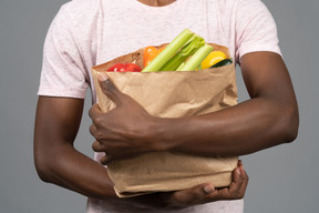 食料品の袋を保持している若い男