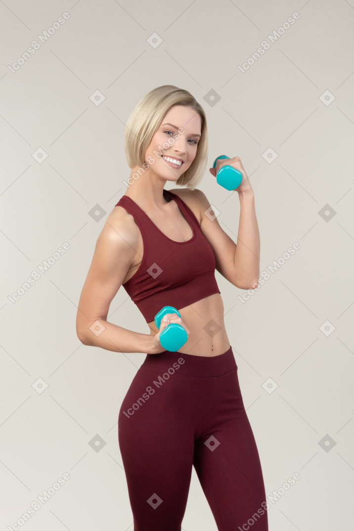 Smiling young woman lifting hand weights