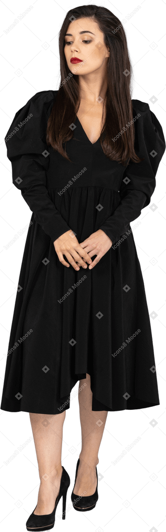Front view of a young lady in a black dress holding hands together