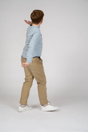 Back view of a young boy raising his hand