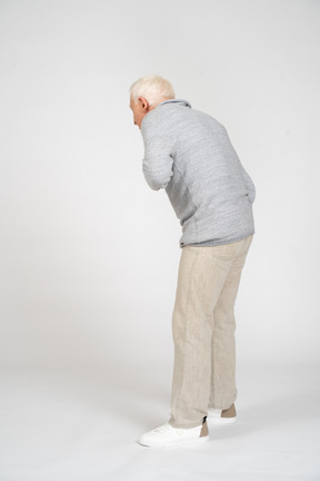 Back view of a man bending down with hand on his chest