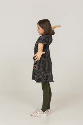 Side view of a little girl in dress outspreading her arms