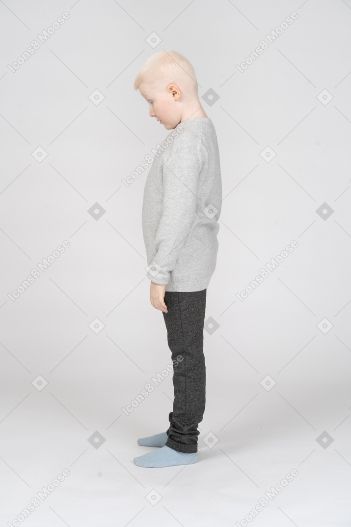 一个小男孩低着头站着不动的侧视图