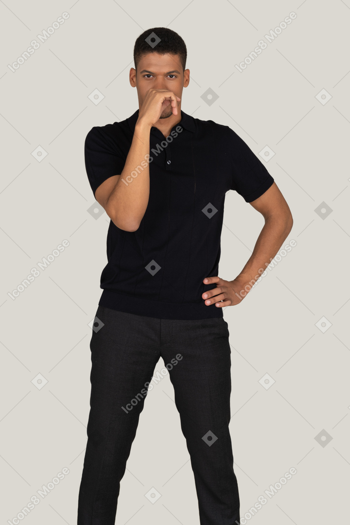 손으로 얼굴을 닫는 검은 색 바지와 티셔츠에 잠겨있는 젊은 남자