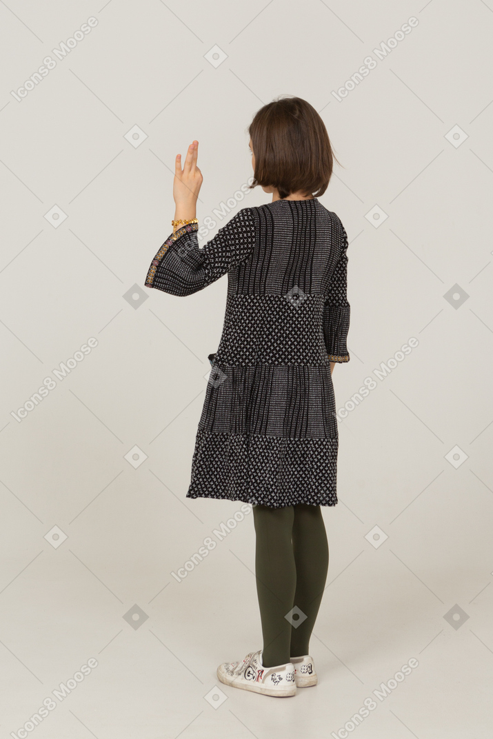 Vista traseira a três quartos de uma menina em um vestido mostrando um gesto de ok