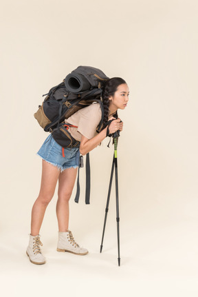 Tired looking hiker woman walking using trekking poles