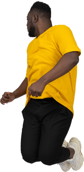 Three-quarter view of a jumping young dark-skinned man in yellow t-shirt