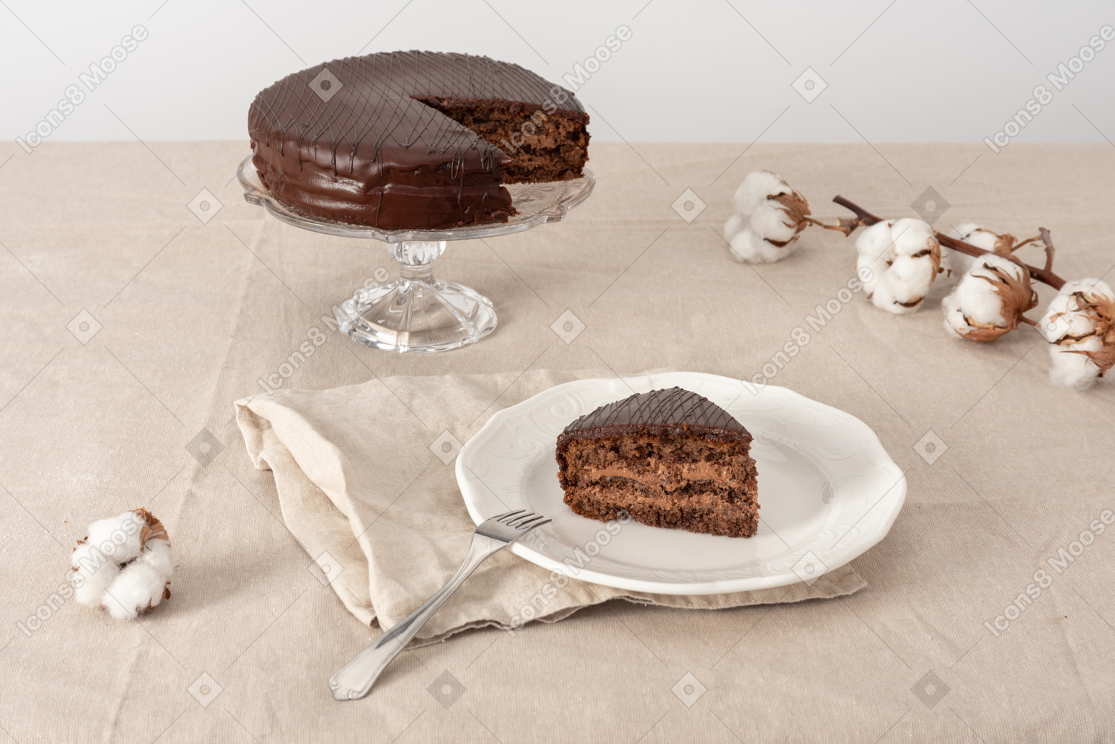 Chocolate caje on cake stand, piece of cake on the plate and cotton branches