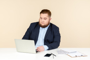 Young overweight office worker sitting at the office desk and working