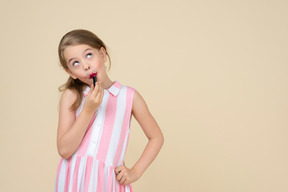 Cute little girl applying red lipstick