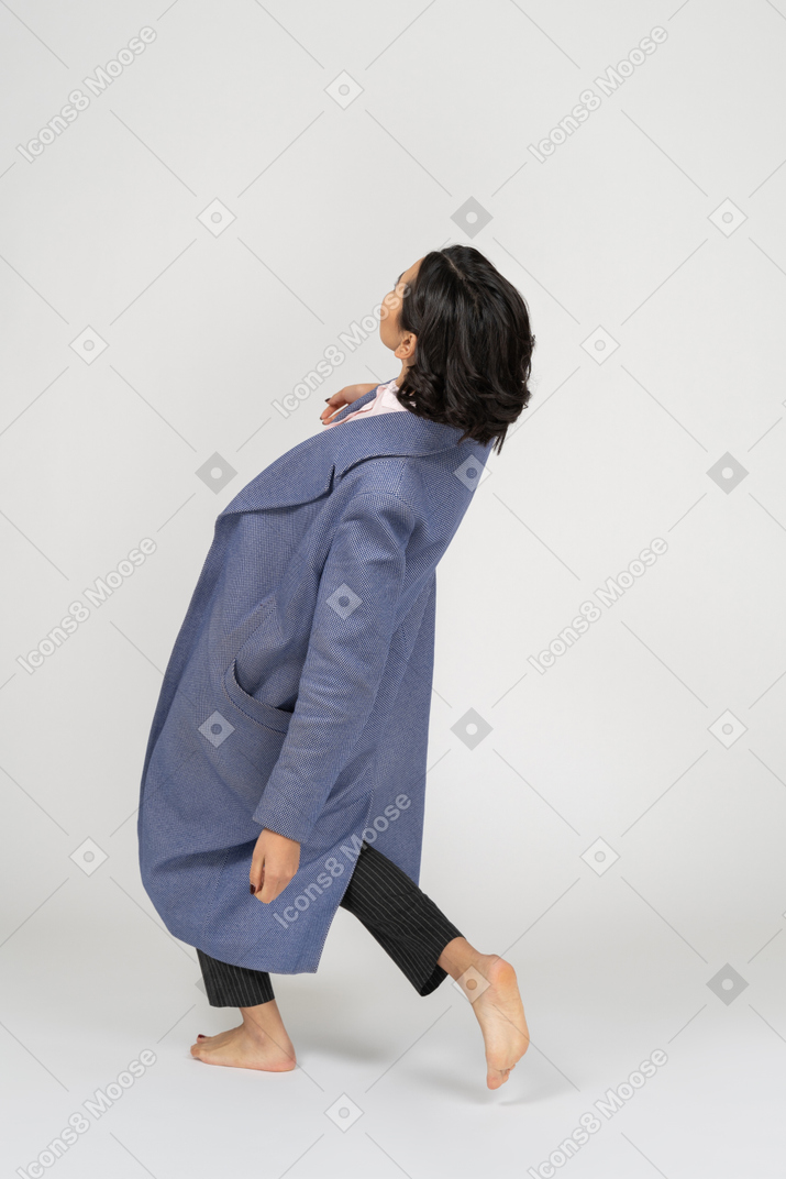 Vista laterale della donna in cappotto appoggiata all'indietro