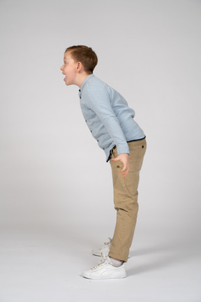 Side view of an angry boy standing with outstretched arms