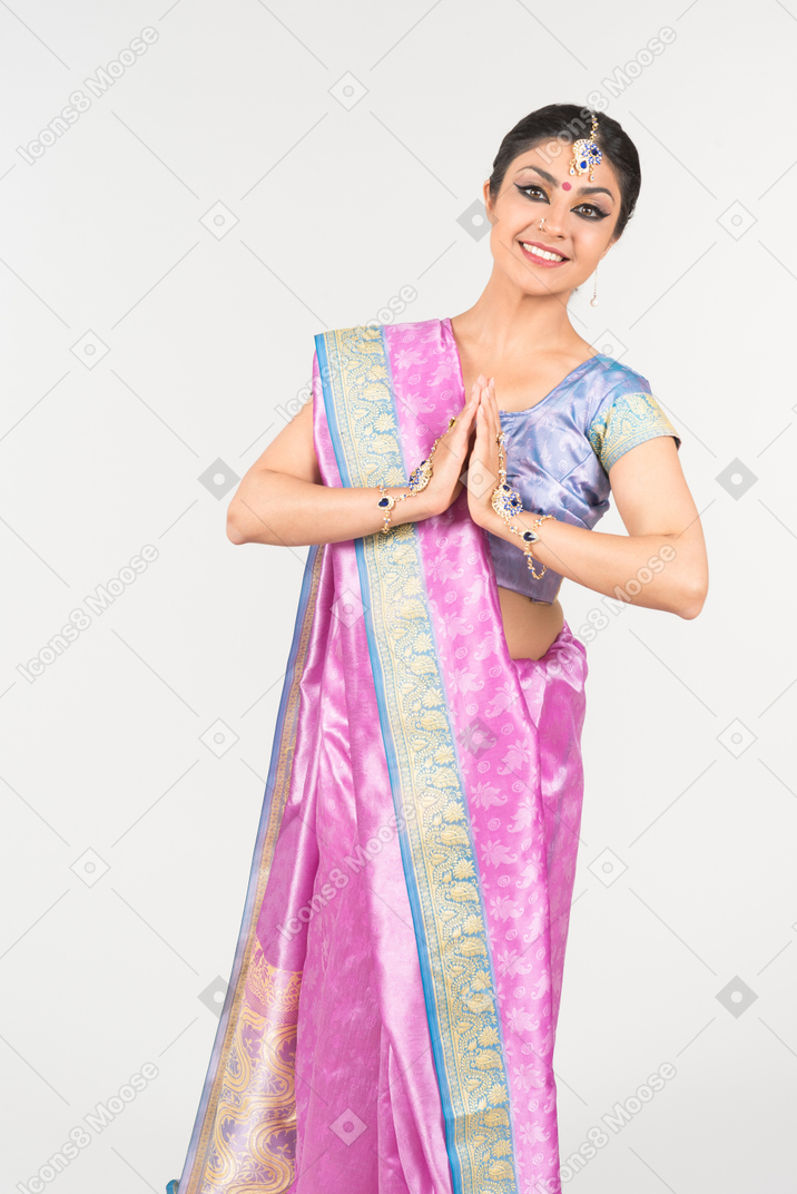 Junge indische frau im purpurroten sari, der ihre hände gefaltet hält