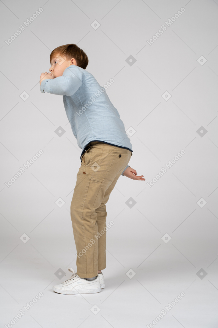 A boy in a blue shirt bending forward