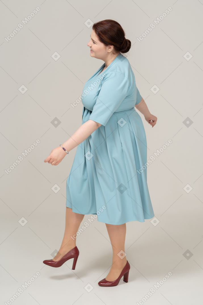 一个穿蓝色裙子的女人走路的侧视图