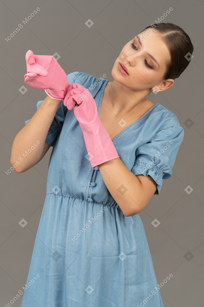 Portrait of a young woman putting on cleaning gloves