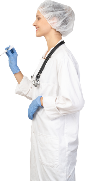 Vista lateral de uma jovem médica com um estetoscópio segurando um termômetro