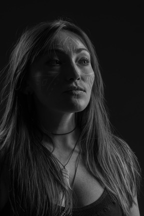 Three-quarter dark portrait of a young  hopeful woman with face art