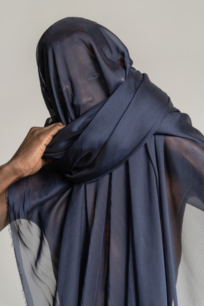 Front view of a young afro man wrapped in blue shawl looking at camera