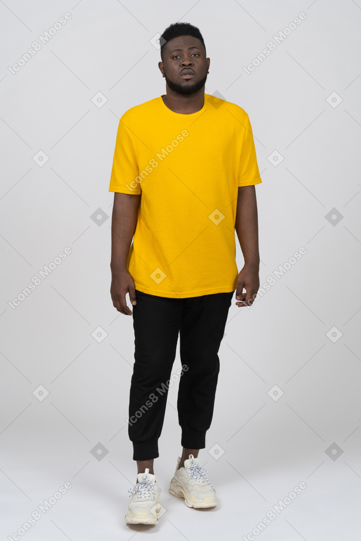 一个身穿黄色 t 恤、站着不动的黑皮肤年轻男子的前视图