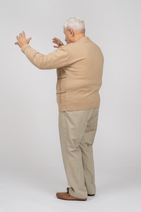 Vista laterale di un uomo anziano in abiti casual che mostra le dimensioni di qualcosa