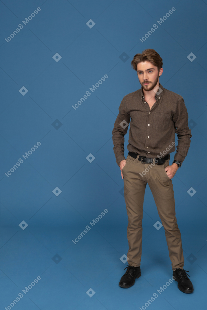 Serious young man standing with hands in pockets