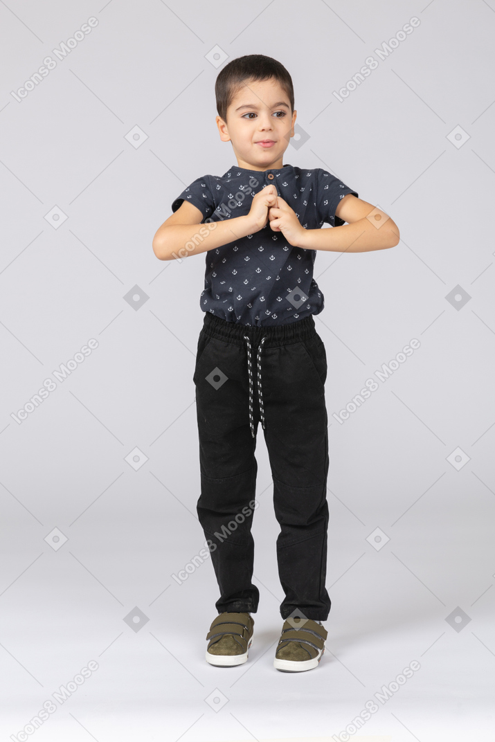 Vista frontal de um lindo menino posando com as mãos na frente do peito