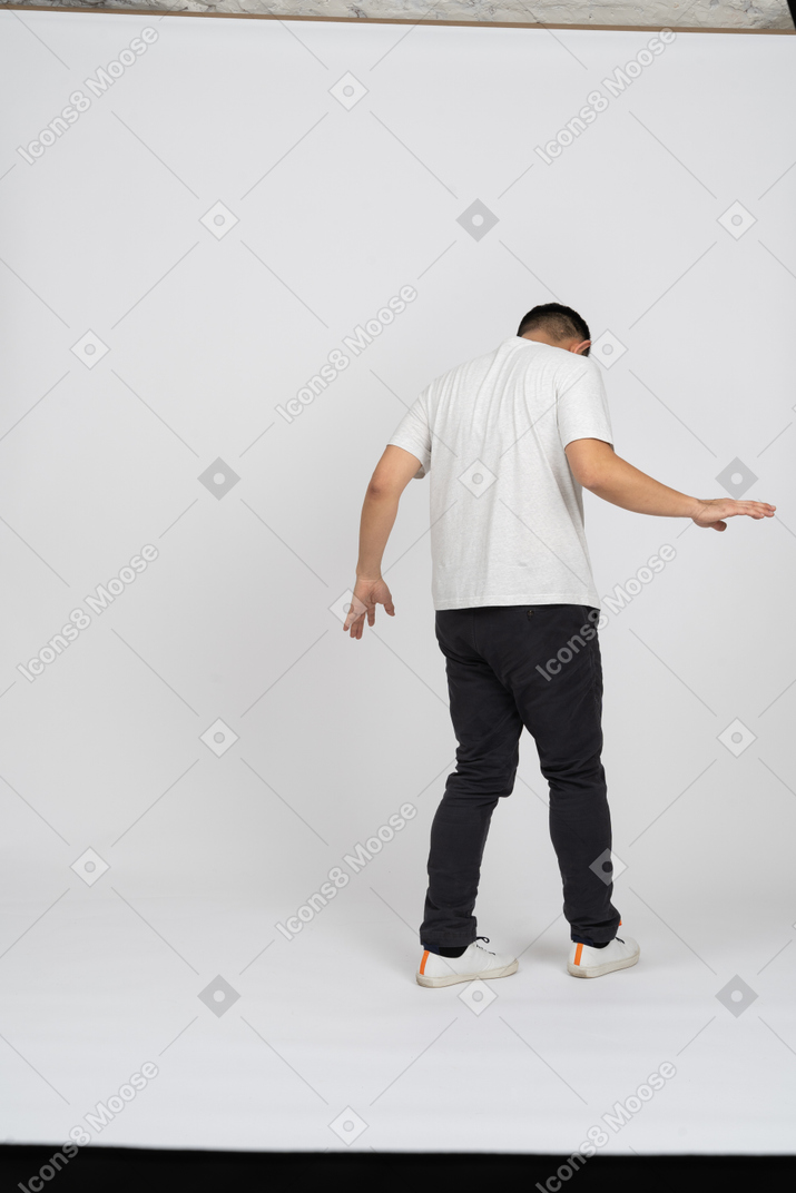 Vista traseira de um homem em roupas casuais andando com os braços estendidos