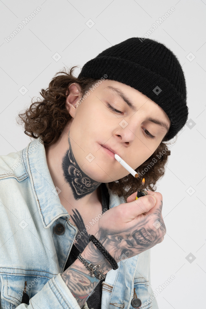 Funky teenager lighting a cigarette on white background