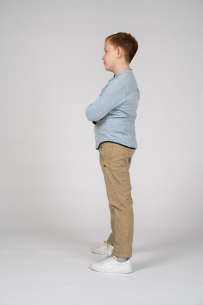 一个可爱的男孩交叉双臂站立的侧视图