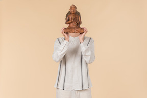 Young caucasian man holding buddha statue