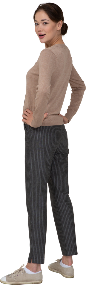 Vista posteriore di tre quarti di una giovane donna in pullover beige che mette le mani sui fianchi