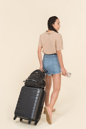 Back view of a young woman with suitcase