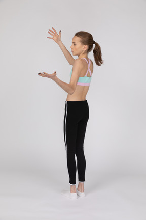Side view of a teen girl in sportswear raising hands and arguing