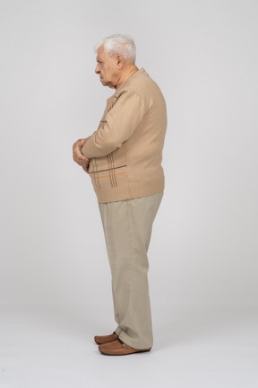 Side view of an old man in casual clothes standing still