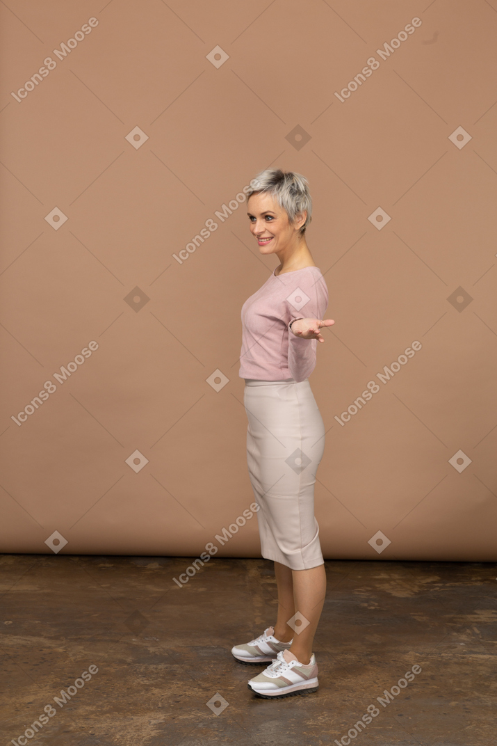 Vista lateral de una mujer en ropa casual de pie con la mano extendida