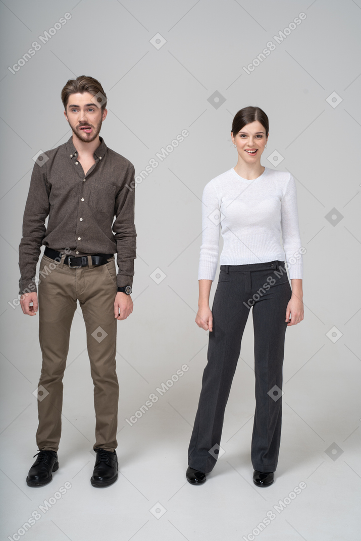 Front view of a smiling young couple in office clothing biting lips