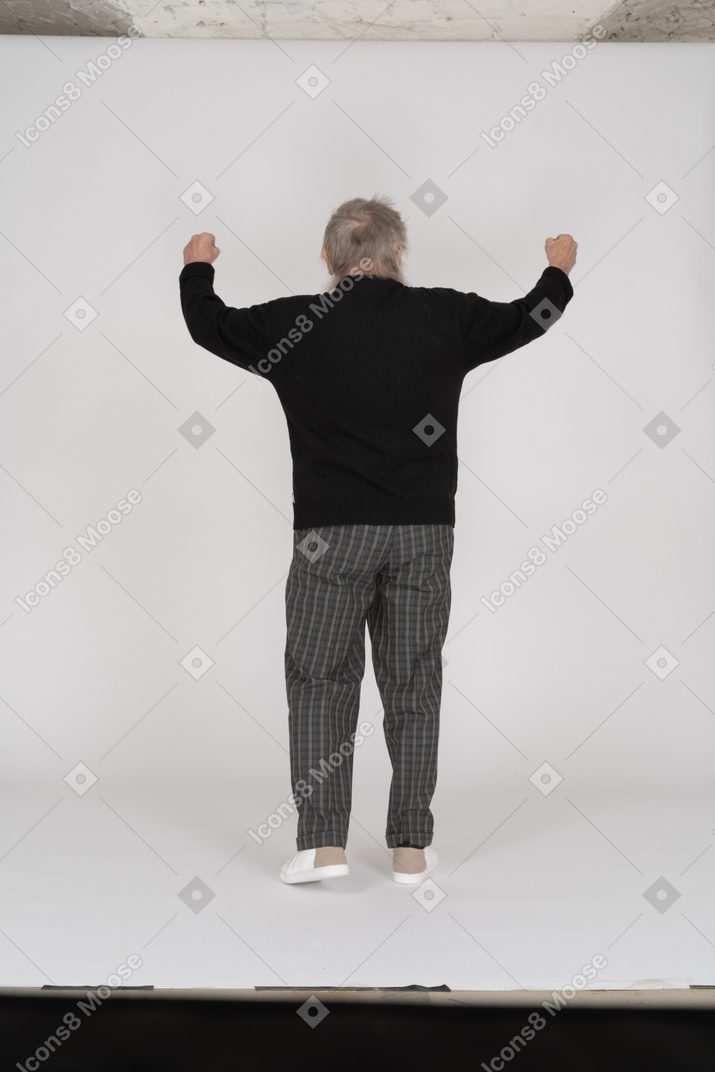 Elderly man with raised arms facing away from camera