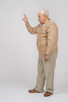 Vue latérale d'un vieil homme en vêtements décontractés montrant le signe v