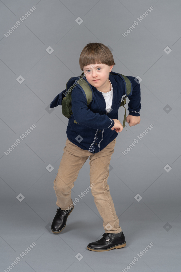 Portrait d'un écolier marchant les bras levés