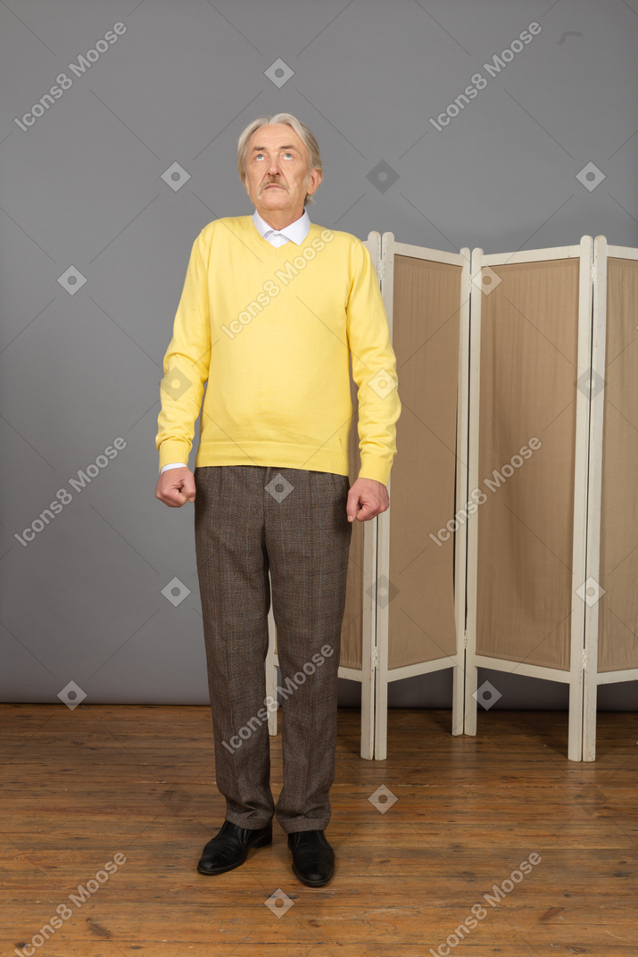Side view of a nervous old man looking up and clenching fists