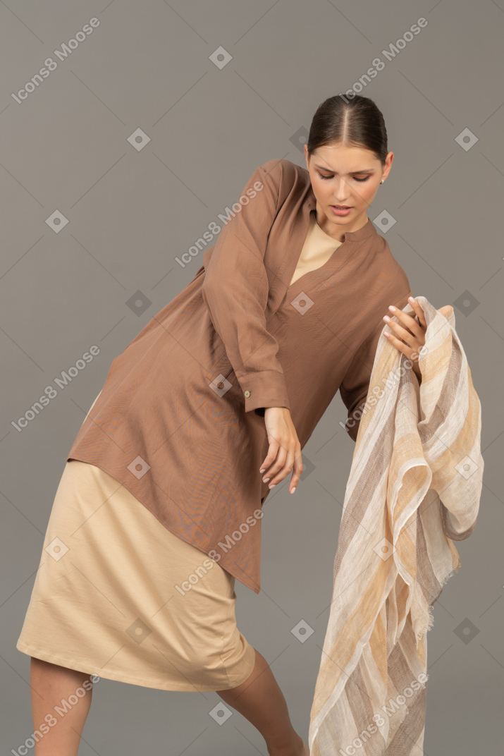 Молодая женщина в бежевой одежде позирует с полосатым шарфом