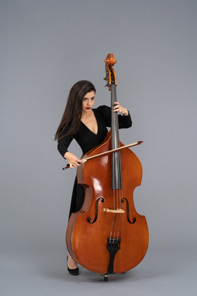 Front view of a young woman in black dress playing the double-bass with a bow