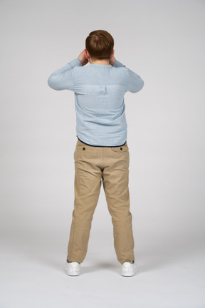 Back view of a boy covering eyes with hands