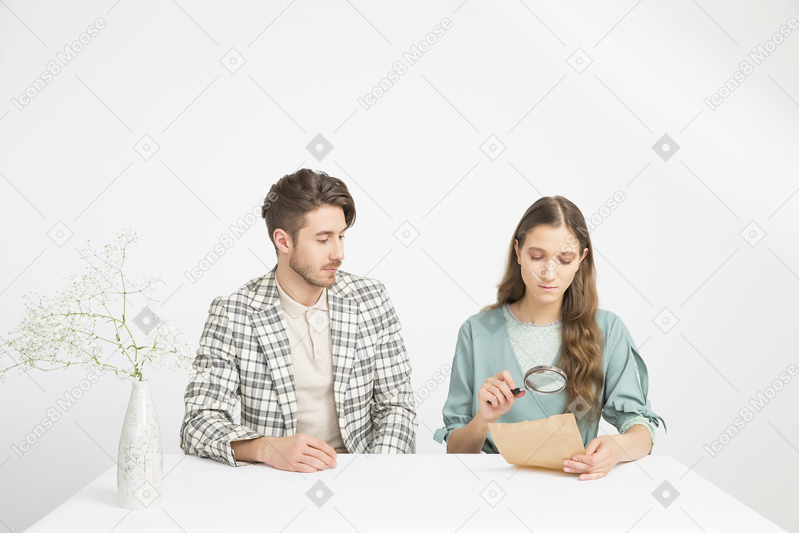 Pareja sentada a la mesa e investigando un papel.