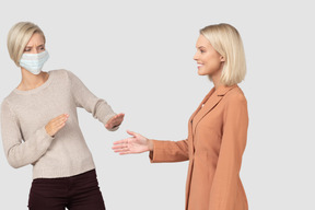 Woman offering handshake to woman in facemask