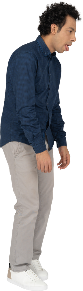 Vista lateral de um homem com roupas casuais mostrando a língua